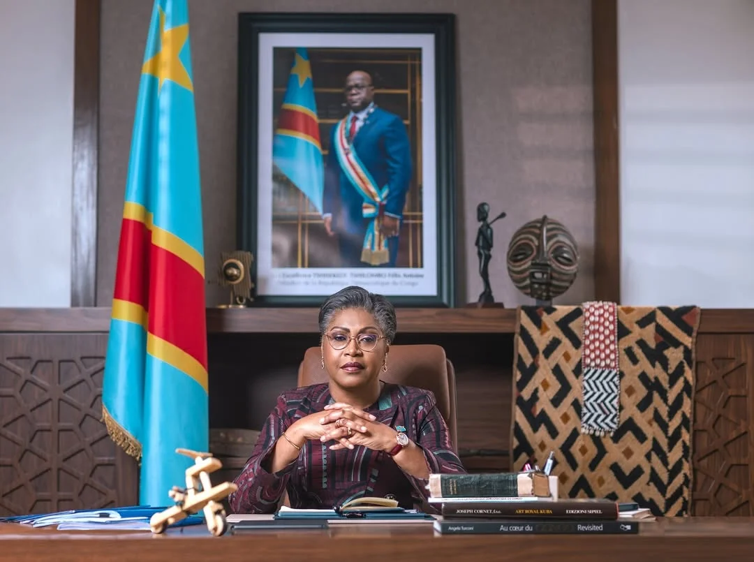 Judith SUMINWA TULUKA dans son bureau de la Primature, devant le drapeau national